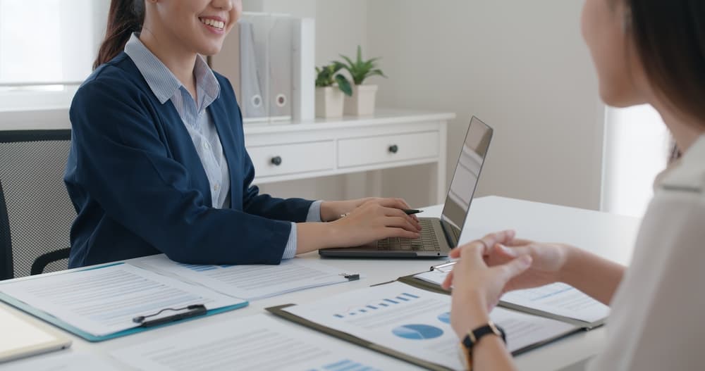 two women sitting at a table with paperwork and charts discussing the financial planning of adopting a child with Down syndrome in Texas