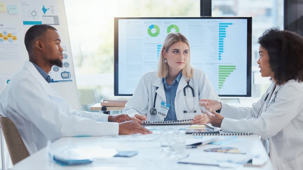 team of three doctors having a discussion at a table with medical charts on a computer behind them as resources for adopting a child with Down syndrome in Texas