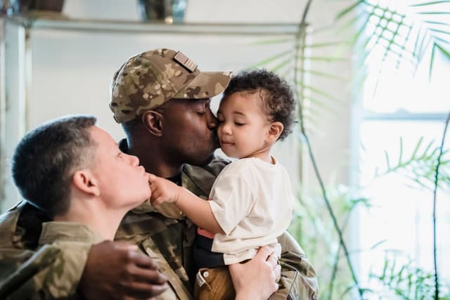 A military parent in uniform holding their newborn after a homecoming