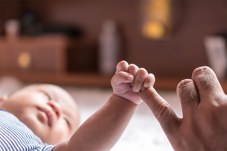 Baby holding adoptive parents finger
