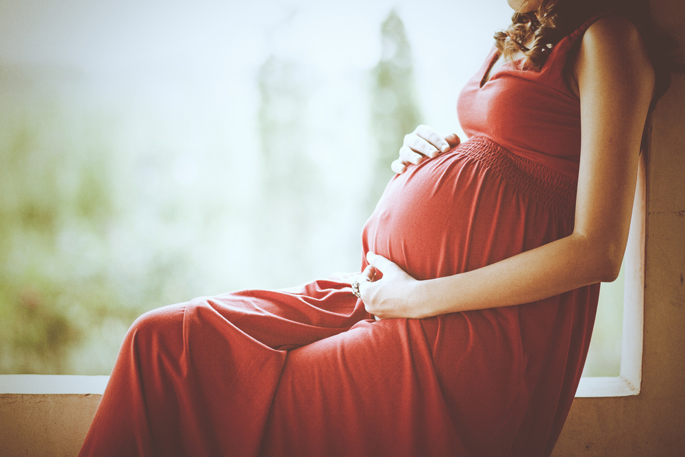 Image of pregnant woman touching her belly with hands