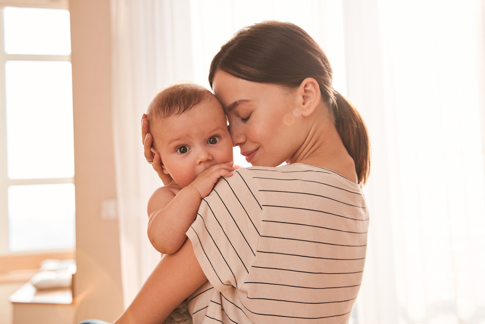 Tender moment. Mother enjoying great time with her lovely baby, while holding him at her hands and bonding with tenderness. Motherhood and happy chidhood concept