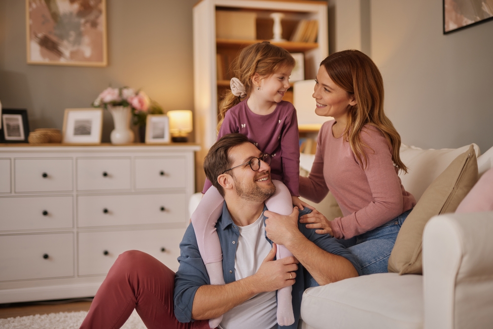Happy family with little daughter sitting on sofa in living room