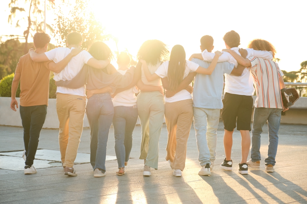 Group of young adults in Texas walks away from the camera with their arms around each other's shoulders, representing a diverse support network for Texas transracial adoption tips and parenting resources