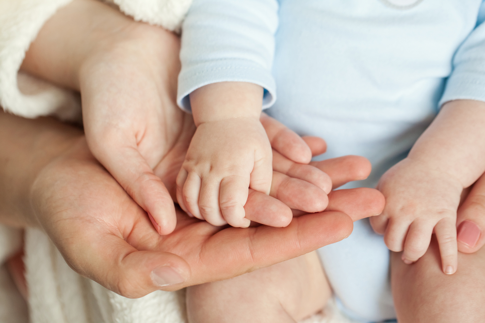 Mom and Dad hold baby's hand