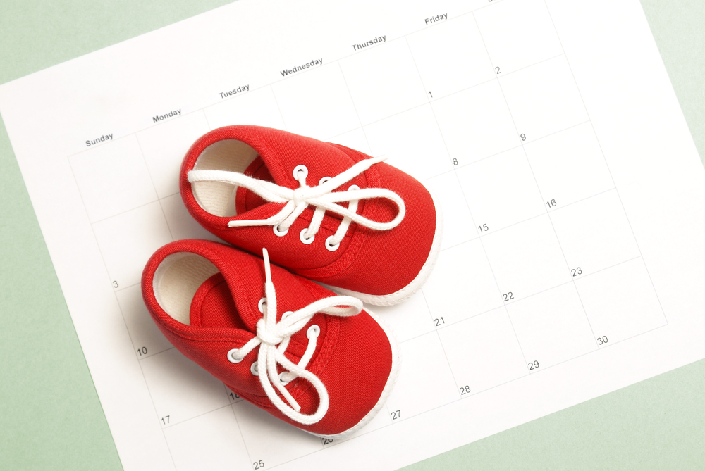 A pair of baby shoes on a monthly calendar to represent many parenting concepts