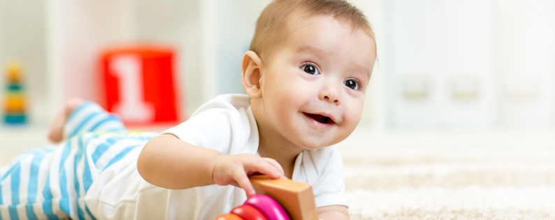 smiling baby boy playing with a stacking ring toy