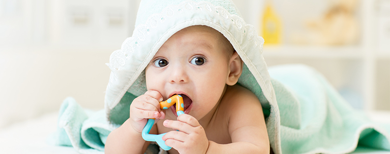 baby wrapped in hooded towel with a toy