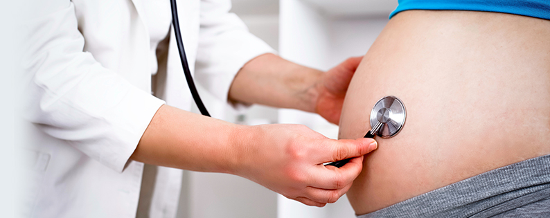doctor listening to a pregnant woman's belly with stethoscope