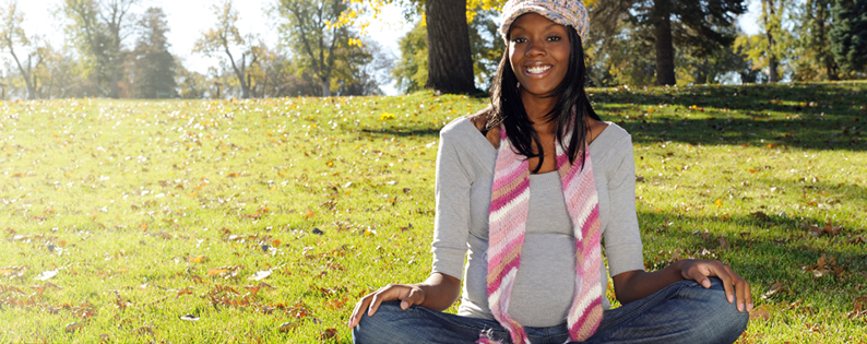 smiling pregnant woman sitting in a field