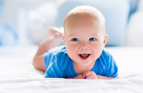 smiling baby boy in blue onesie