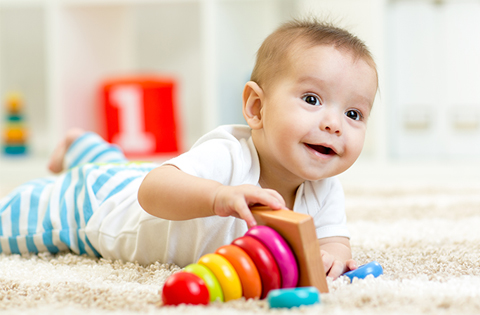 smiling baby boy playing with a stacking ring toy