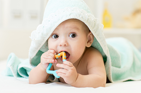 baby wrapped in hooded towel with a toy