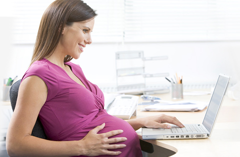 pregnant woman at a desk with a computer