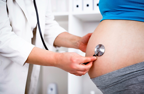 doctor listening to a pregnant woman's belly with stethoscope