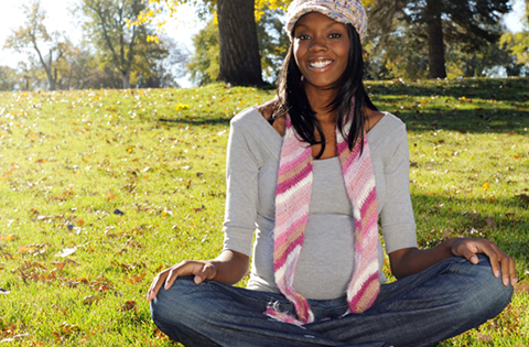 smiling pregnant woman sitting in a field
