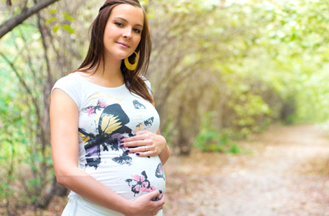 smiling pregnant woman on a wooded path